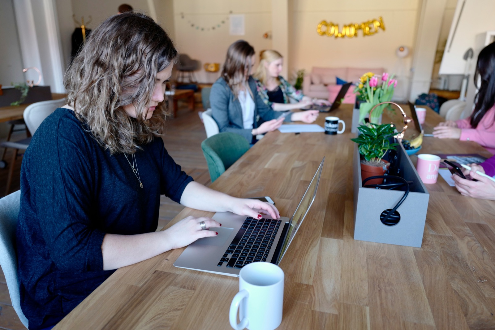 Mehrere Unternehmerinnen im Coworking-Space mit Laptops