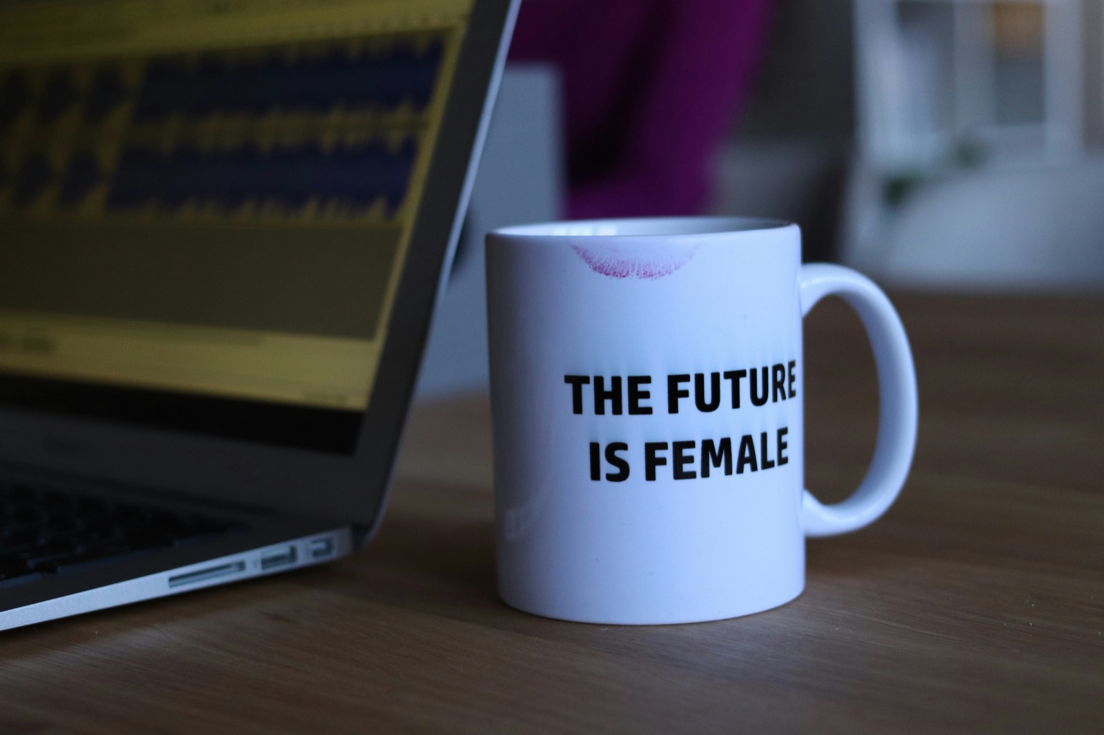 Kaffeebecher mit Aufschrift The Future is Female neben einem Laptop
